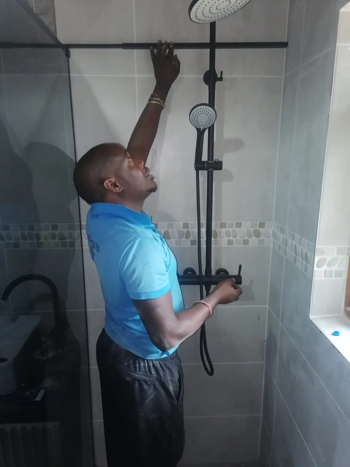 Plumb A Nator technician checking a black shower mixer and rail set during a Randburg bathroom plumbing job.