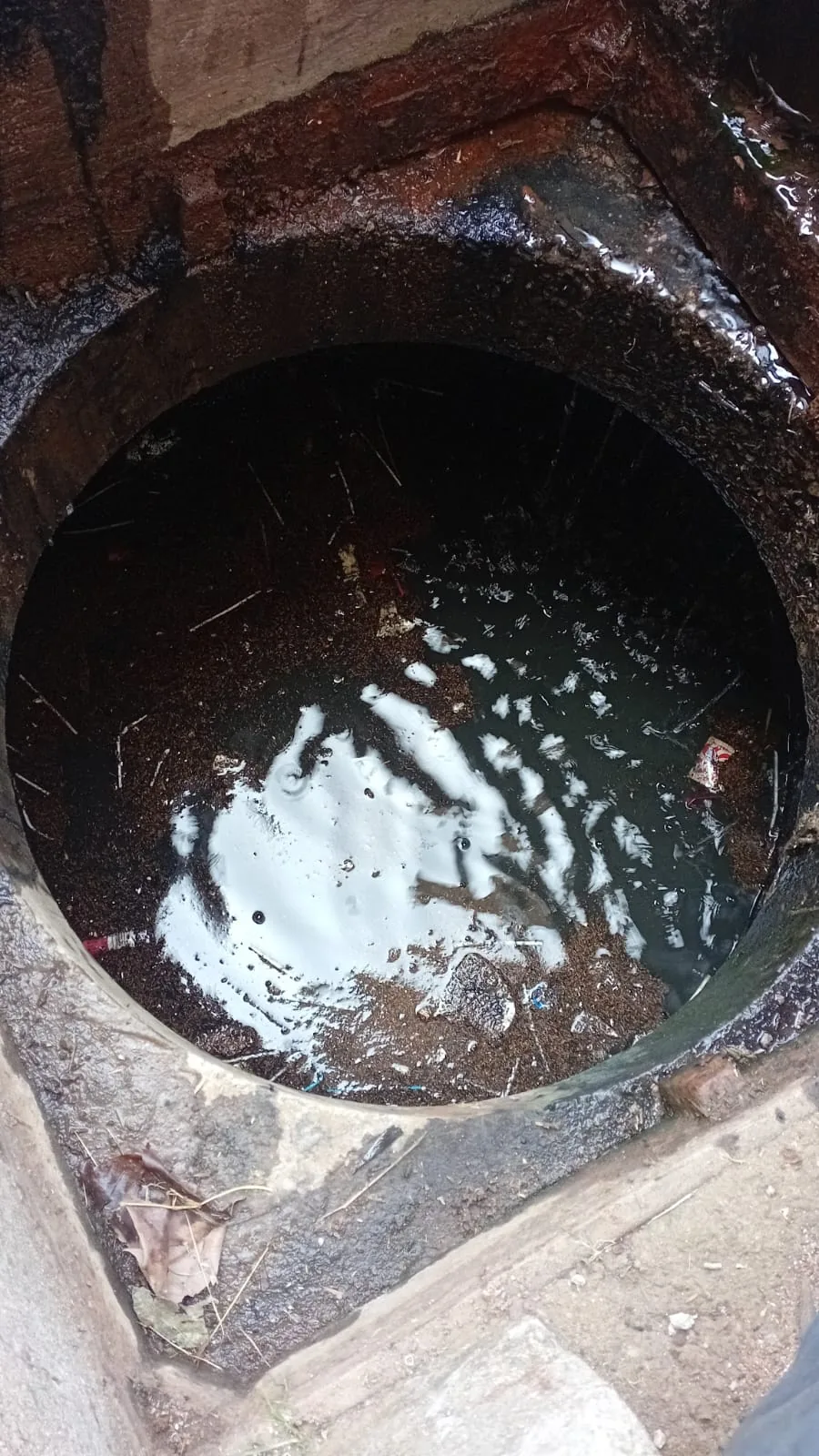 Open blocked drain chamber with standing wastewater during a Randburg drain clearing callout.