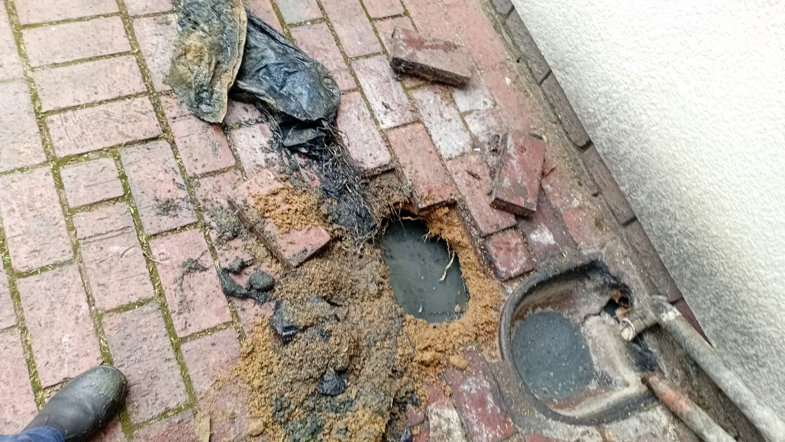Excavation at an outside drain point linked to a deeper toilet branch-line blockage.