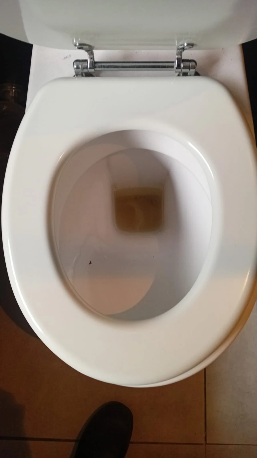 Toilet bowl showing retained water during a pan-level blocked-toilet assessment.