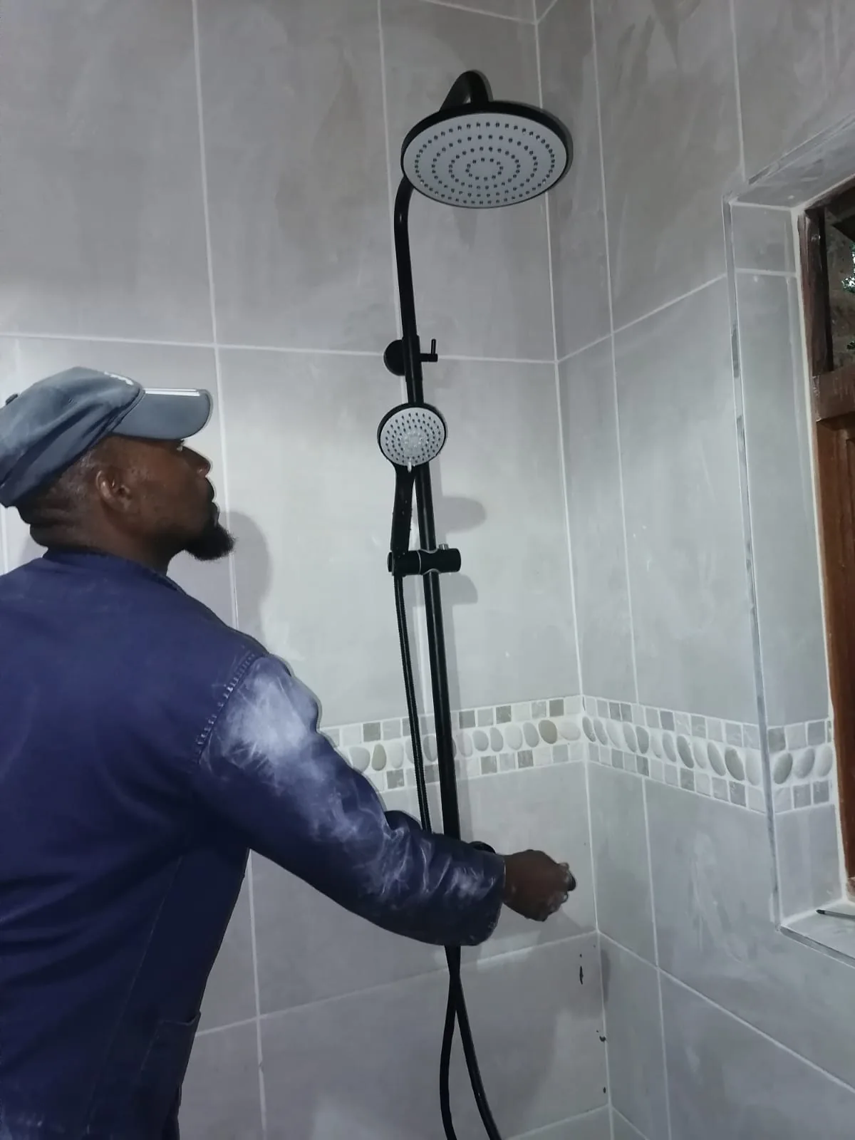 Technician inspecting a black shower set during a Bromhof plumbing service call.