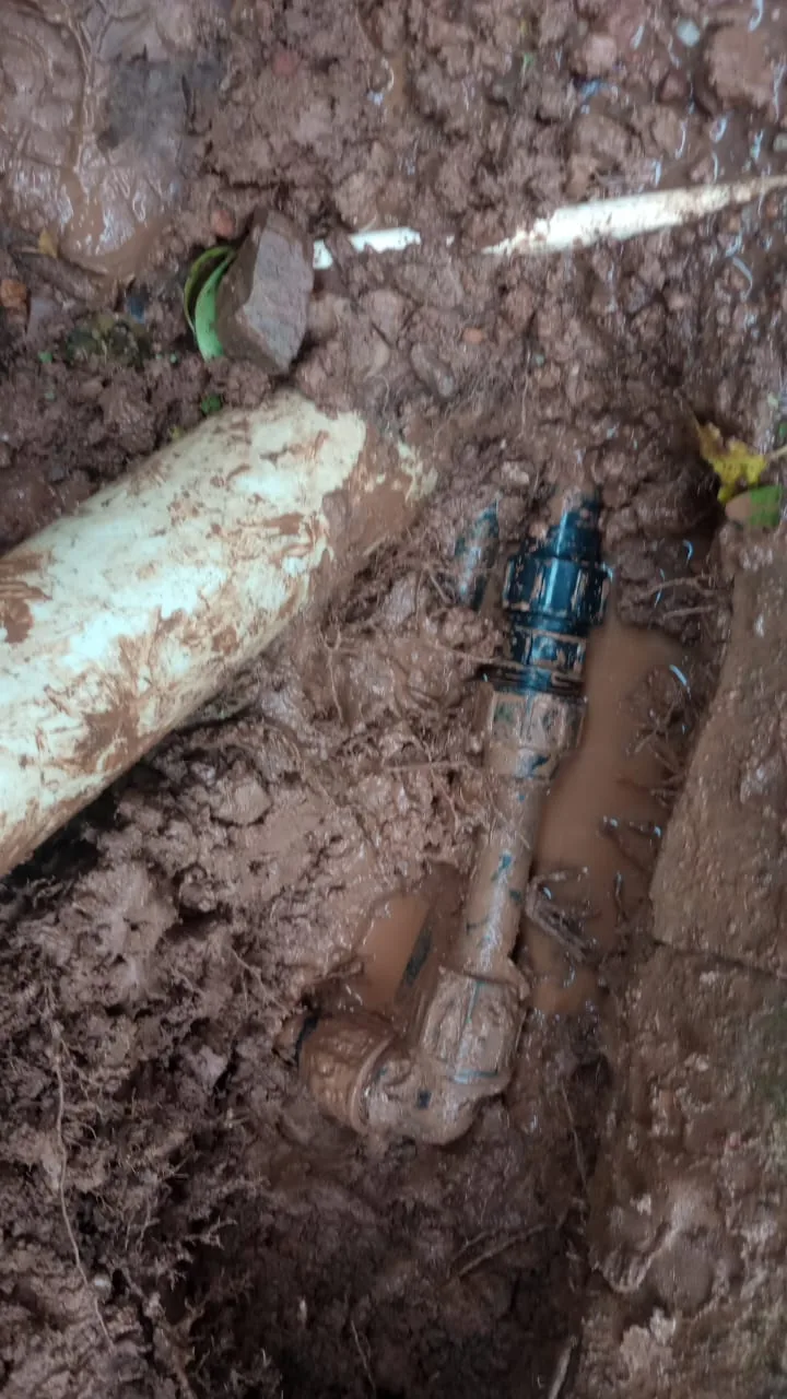 Exposed muddy underground pipe repair with coupling during a Randburg burst pipe repair.