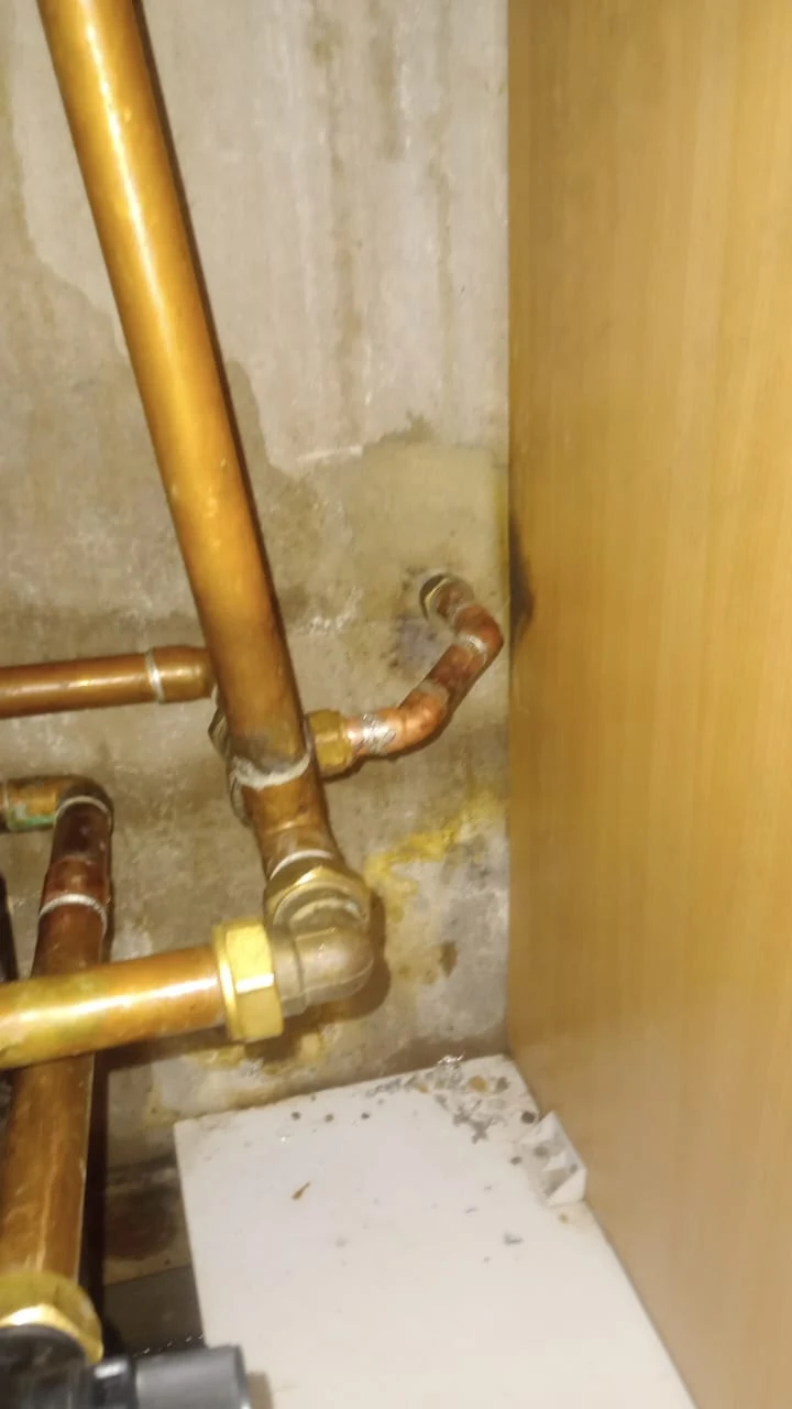 Visible burst pipe repair on copper pipework inside a cupboard area.