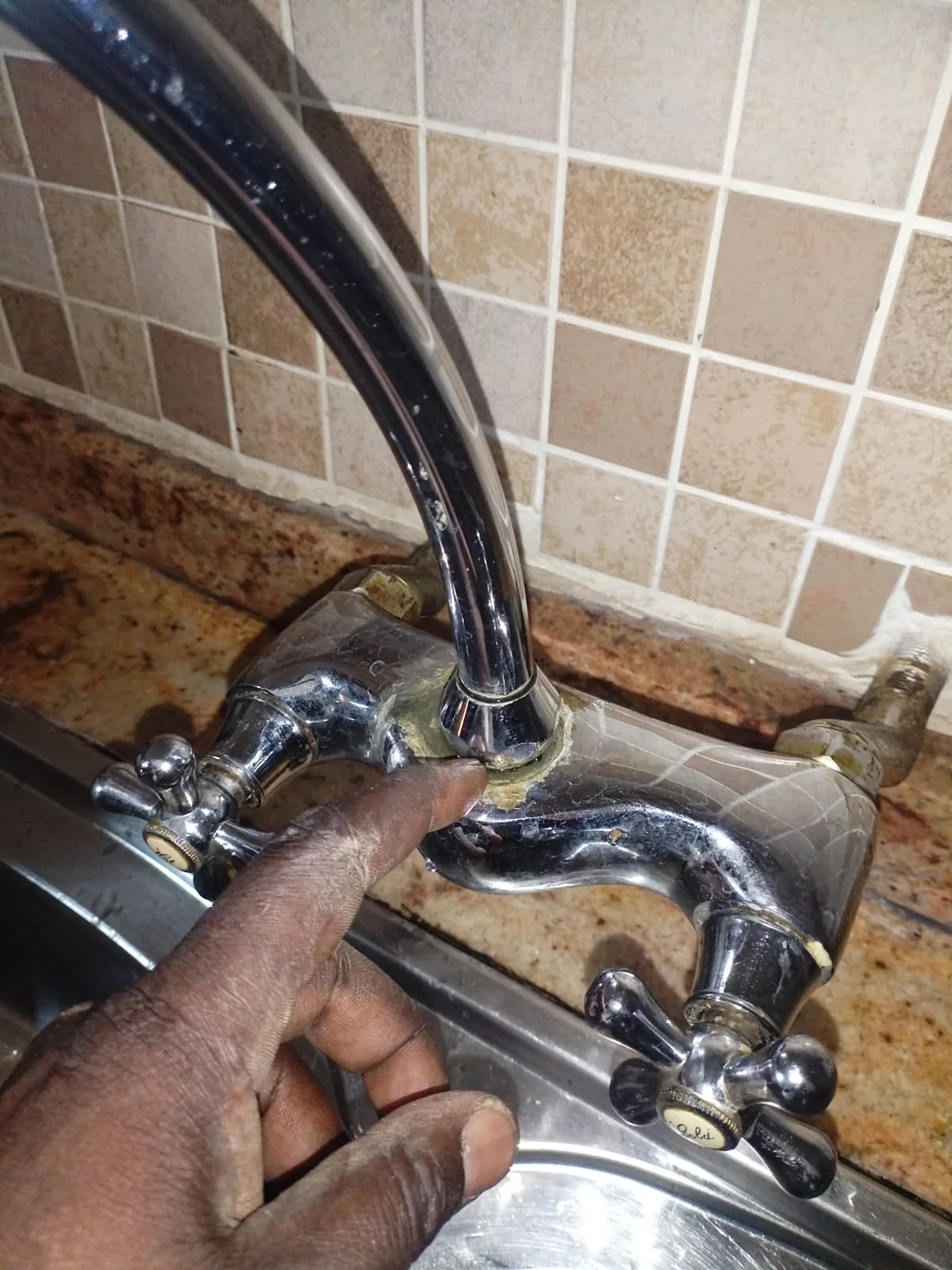 Technician pointing to a leaking kitchen mixer base during a Ferndale plumbing repair.
