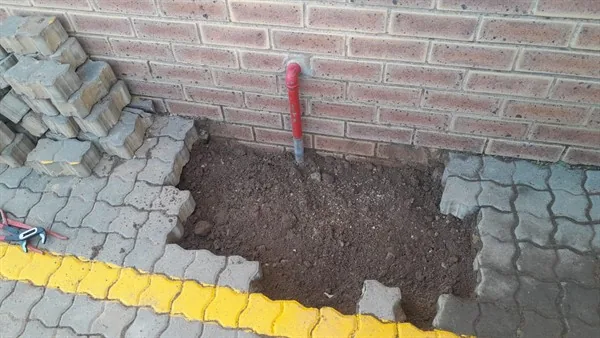Excavated paving and exposed pipework after locating an underground leak.